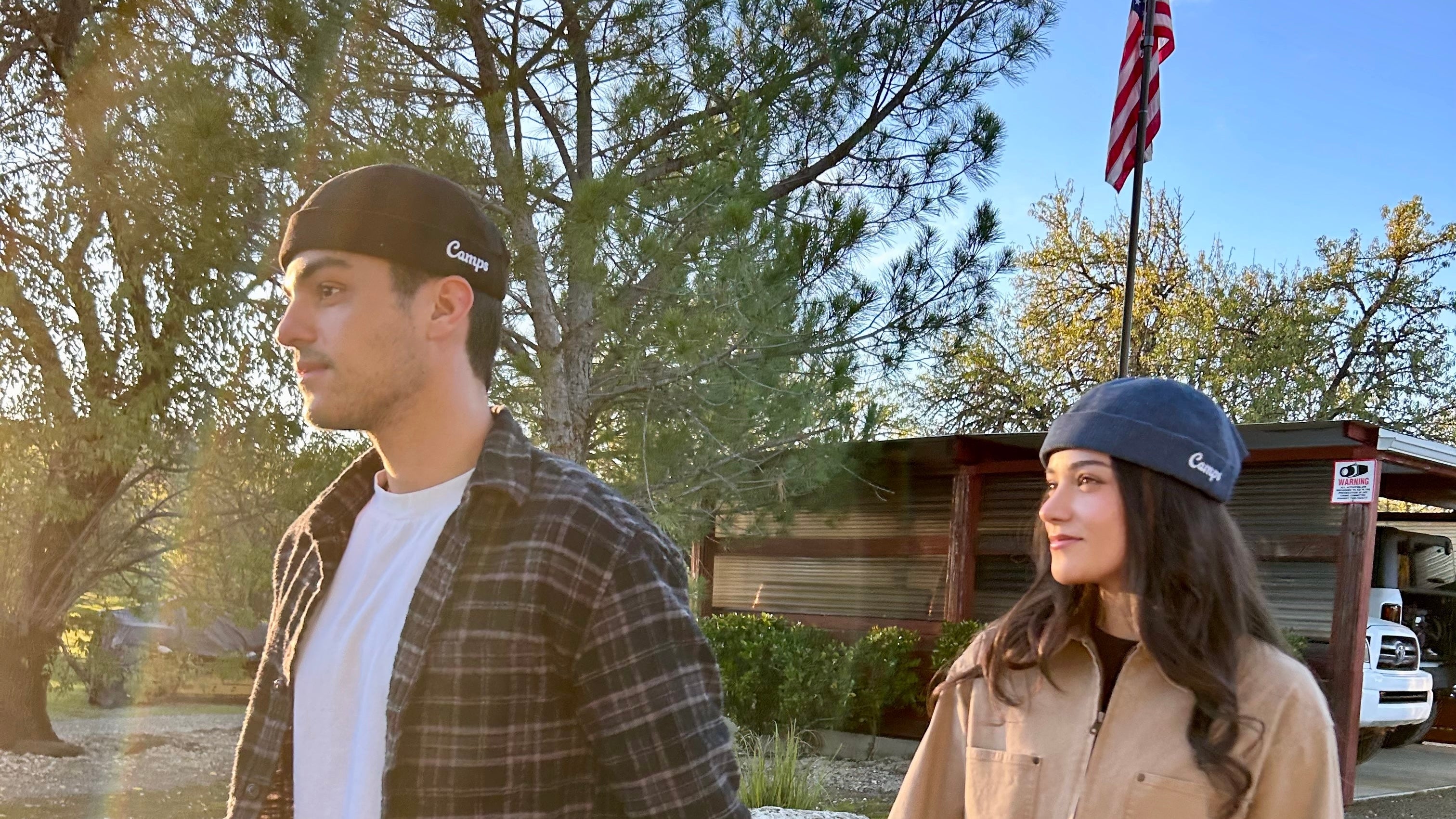 Two people holding hands on a road with trees and a building in the background