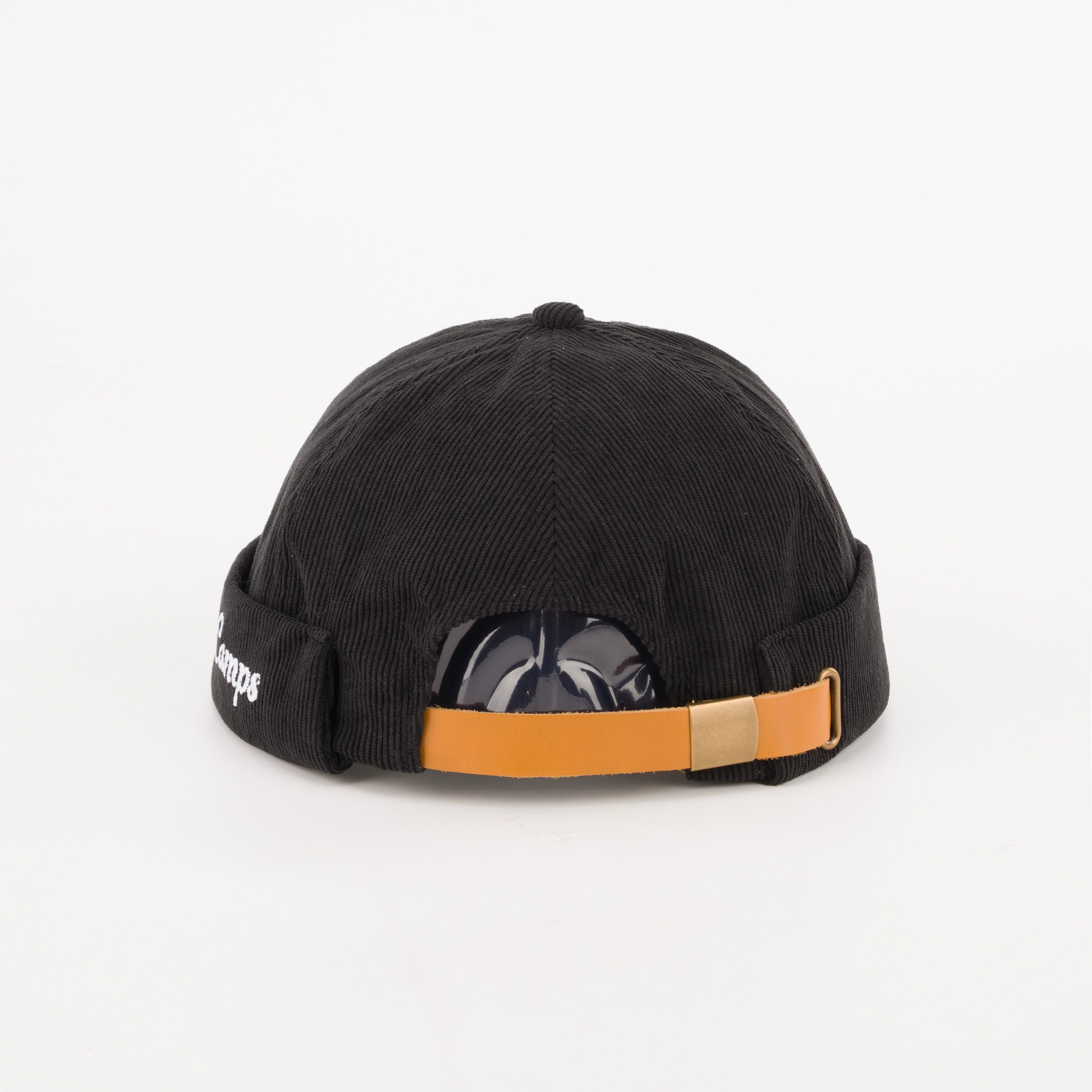 black corduroy brimless hat post production. Tan leather strapback